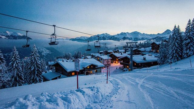 Alpine village under fresh snow with lift cables above the rooftops