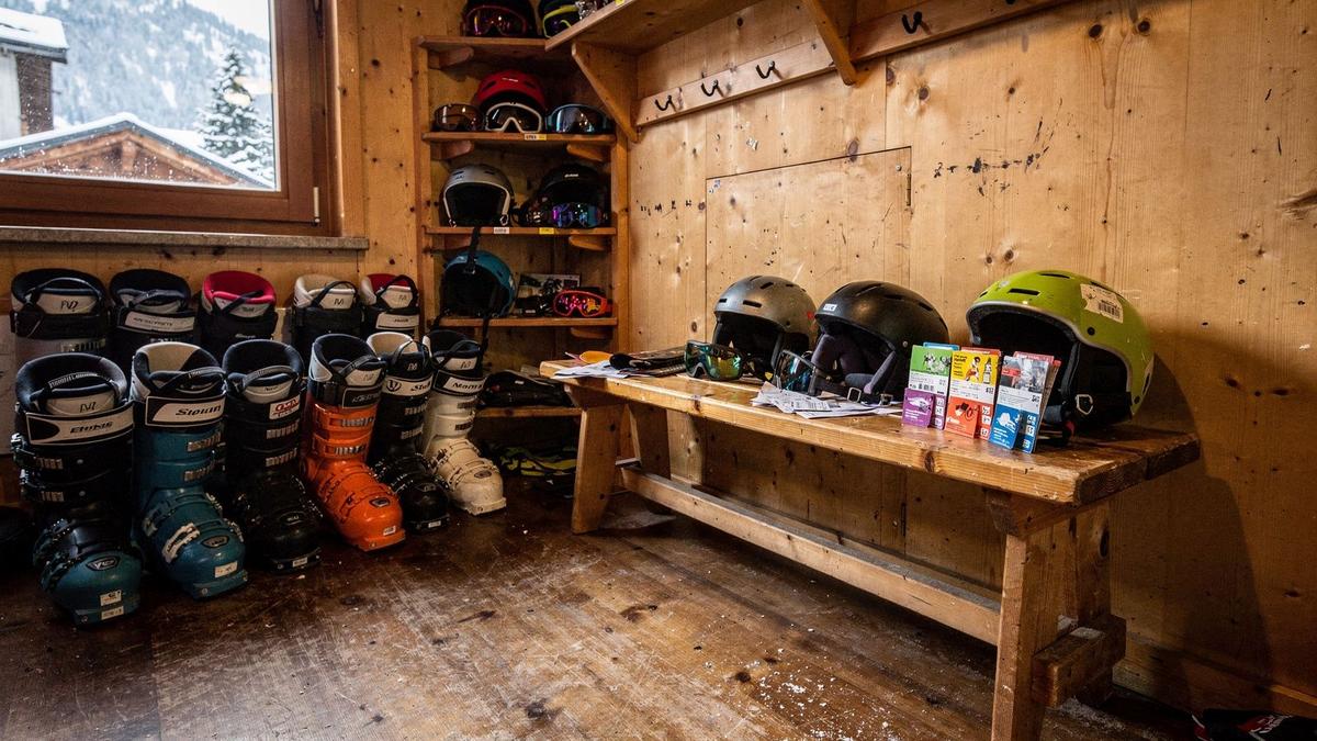 Ski equipment, helmets and lift passes laid out in a chalet boot room before departure