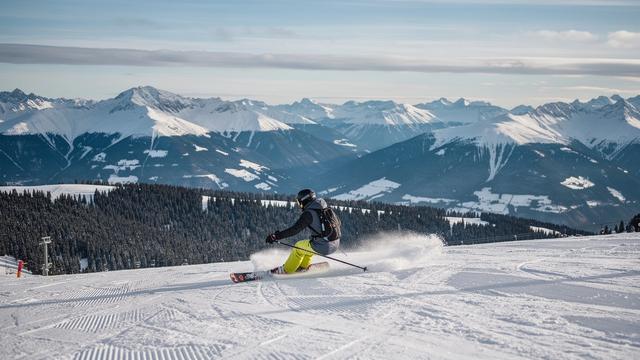 Skier on a groomed piste above the tree line in the Alps