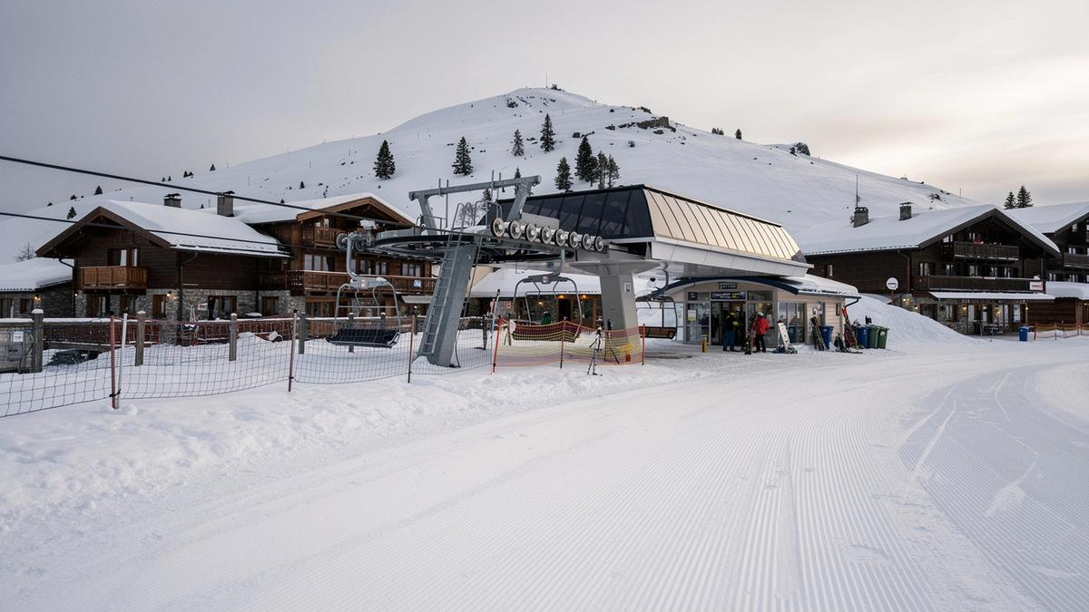Ski lift station and groomed piste in the Alps seen from the arrival road